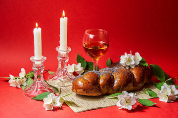 Challah bread, shabbat wine and candles on red background. Lighting a candle. Shabbat Shalom - obrazy, fototapety, plakaty