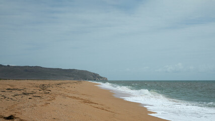 A deserted sandy beach with an incoming foam wave.  Copy space.