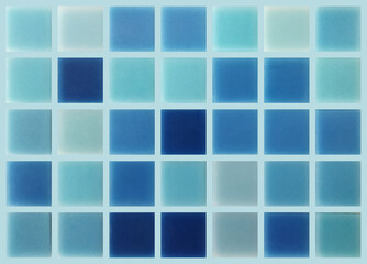 The texture of the tile with square elements of blue shades. Blue and turquoise squares on a light background.
