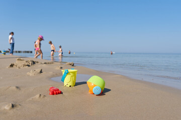 Children toys and children in summer on the beach of the Baltic Sea coast near Kolobrzeg in Poland - obrazy, fototapety, plakaty