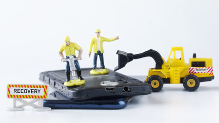 Toy man workers repair a mobile phone or smartphone using a jackhammer and a forklift truck. Concept for repairing, launching recovery mode and restoring smartphone. Macro