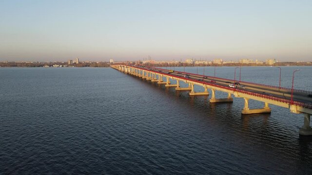 Cars and buses travel along the road on long bridge over the river, bay. drone view, aerial photography. Bridge over the Dnieper, urban transport in city Dnipro, Dnepropetrovsk, Ukraine