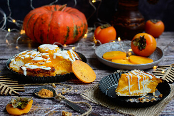 View of curd cake with pumpkin and cream cheese and persimmon on a wooden background. Autumn desserts
