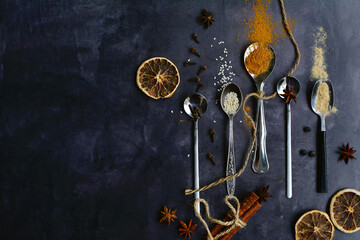 Fragrant autumn spices for baking on spoons on a dark background. Copy space. View from above.