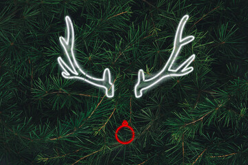 Christmas reindeer concept made of neon on  evergreen fir background. Minimal winter idea with xmas...
