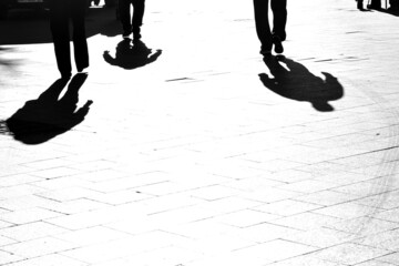 Human feet and shadows on pedestrian street tiles