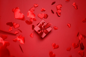 Valentines Day festive card, gift box with ribbon and falling satin hearts on red