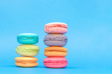 Fresh Colorful Macarons Stacked Into Two Pyramides  On The Blue Background.  Isolated French Sweet Macaroons. Side View. Text Place.