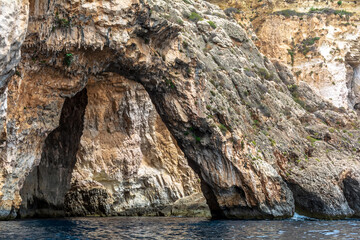 Rocky edges of the Blue Grotto, Malta, sticking out from Mediterranean Sea and lit by the morning sun. Rock formations with caves.