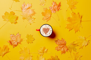 Cup of coffee with heart shape and maple leaves around