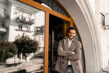 Handsome bearded business man in coat posing outside. Male lifestyle.