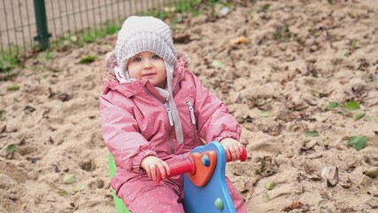 Sweet Happy Cute Adorable Caucasian Toddler Girl in Warm Autumn Clothes Playing on Public Playground Spring Rocker Horse