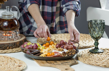 Appetizer for guests. A plate with cheese, salami, nuts, grapes and snacks on a black iron plate. Antipasto. Italian cuisine.