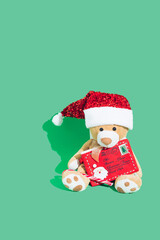 Christmas and New Year background. Bright Winter holiday composition. Greeting card, poster. Cute teddy with candy cane and letter for Santa. Green background.