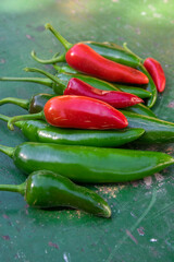 Capsicum annuum Jalapeno chilli hot peppers, group of green and red fruits on wooden colorful table background