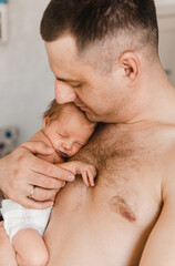 Portrait of father holding sleeping newborn son on his arm. Newborn baby in diaper in father's hands. Selective focus. Film grain
