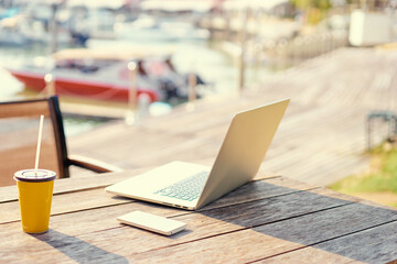 Comfort workplace. Laptop computer and cup on wooden table outdoor.