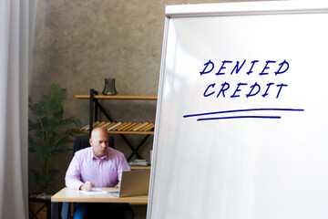 Business concept about DENIED CREDIT with phrase on the White Board. Banker working at work table