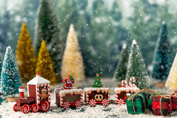 Christmas scene with a red train between evergreen trees in snow