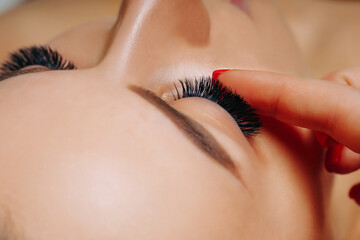 Eyelash Extension Procedure. Woman Eye with Long Eyelashes. Close up, selective focus. - 468845740