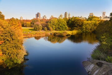 Golden Autumn in Central Park in New York city. Amazing landscape with The Central Park Turtle Pond, colorful trees and buildings on the background.