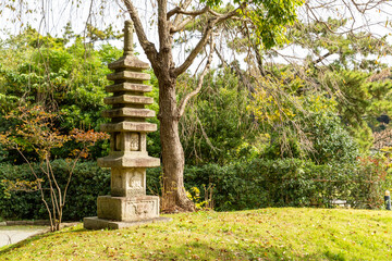 stone tower standing on the small hill in autumn japanese garden