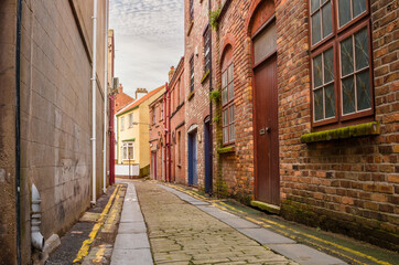 Fototapeta premium Deserted stone alley lined with old brick buildings in a town centre