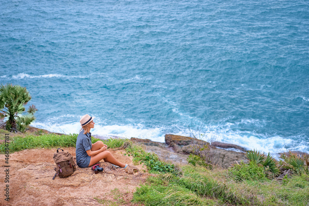 Wall mural Travel concept. Young woman with camera and rucksack enjoying the sea view.