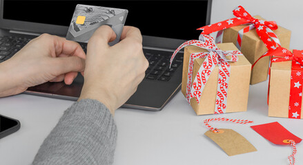 Online shopping during holidays. Woman ordering Christmas gifts using laptop and credit card.