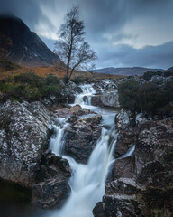 Fototapeta na wymiar Waterfall and the lone tree in Glencoe, Scottish Highlands.Blue hour landscape scenery.