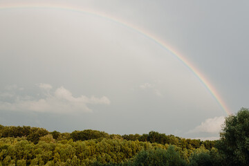 Rainbow after rain on cloudy sky