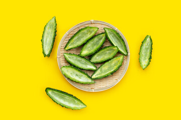 Bitter gourd in bamboo basket on yellow background.