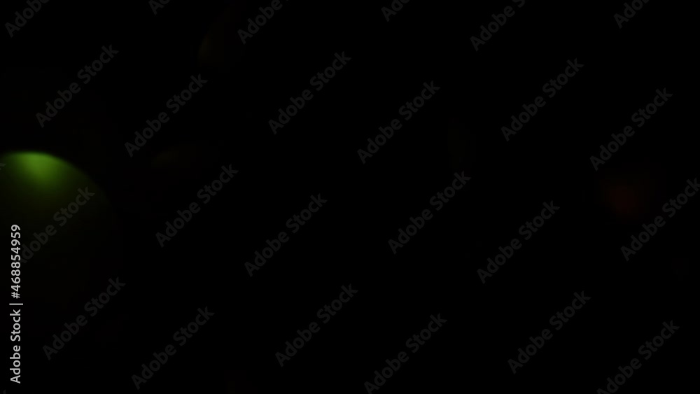 Wall mural rapid movement of light over dark bokeh. rounds of illuminated light move from left to right on a da