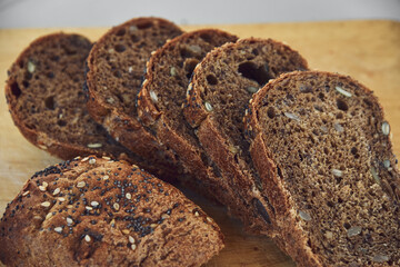 Sliced rye bread with sunflower and poppy seeds on rustic wooden background. Healthy food still life
