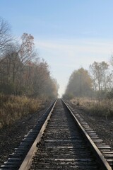 Obraz premium View Down Railroad Tracks Disappearing into Foggy Hazy Horizon 