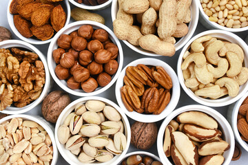 Colorful mix of various nuts: peanut and cashew, hazelnut and almond, pine nuts and walnut; healthy diet snack; vegan food background