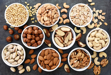 Colorful mix of various nuts: peanut and cashew, hazelnut and almond, pine nuts and walnut; healthy diet snack; vegan food background