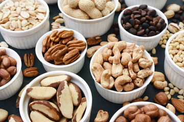 Colorful mix of various nuts: peanut and cashew, hazelnut and almond, pine nuts and walnut; healthy diet snack; vegan food background