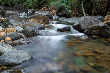 Naklejka na ściany i meble slow shutter speed of soft water and rocks river in jungle 