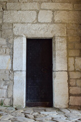 The gates of an old medieval castle or fortress, covered with strips of iron. The gate has a closed wicket with a handle