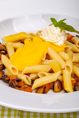 Penne pasta with pumpkin, tofu and mushrooms on white plate. Close up