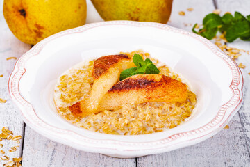 Oatmeal porridge with pear in white plate. Close up