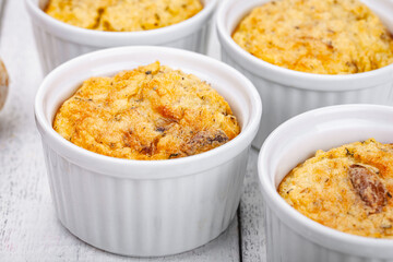 Polenta with mushrooms in white ramekin bowls on wooden rustic table. Close up