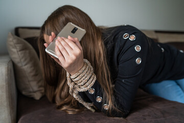 Unknown caucasian woman victim of human trafficking reaching for her mobile phone trying to call...