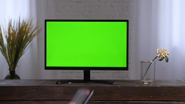 Control remote hand changing channels TV screen plasma panel. Smart television remote. Flat screen Lcd tv home watching television mockup. Living room tv green chroma key screen television set 2000s