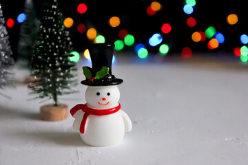 Cute snowman and Christmas tree on colorful bokeh lights background. New year or Christmas...