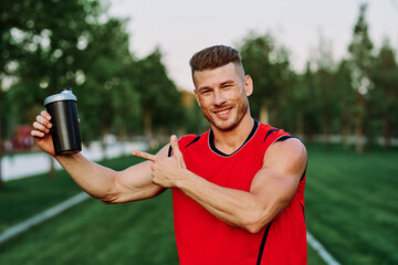 Fototapeta premium Cheerful sporty man in the park on green grass doing exercises