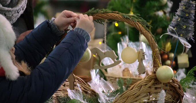 Girl decorates a basket with decorative toys. Festive mood. Christmas preparations. 4k. Slow motiom