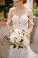 Bride with a bouquet of flowers is standing indoors