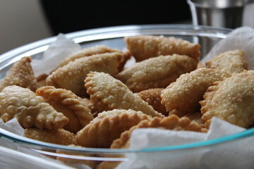 Freshly made Ghughra (Gujarati Indian crispy fried snack food with sweet, dry filling) in a glass container for Diwali